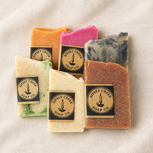 Six artisan soap bars from Sipsey Creek Soap Co. arranged on a white fabric background.